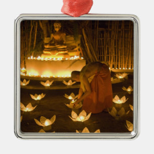 Monks lighting khom loy candles and lanterns for metal tree decoration