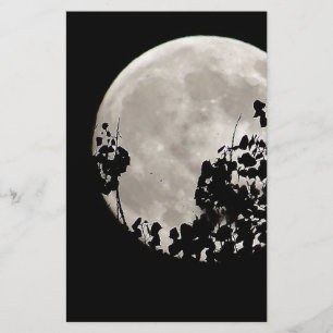 Moon behind dark leaves