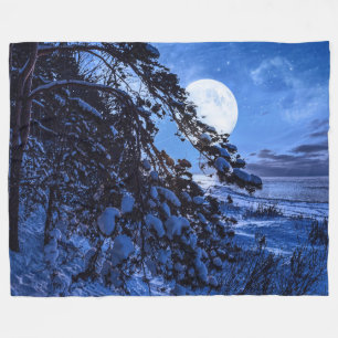 Moon over snowy fir tree and sea coast at night fleece blanket