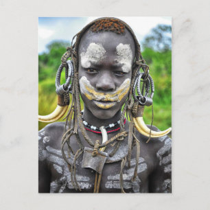 Mursi boy with painted body and tusk headdress postcard