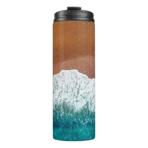 Ocean wave on a sandy beach, background top view thermal tumbler