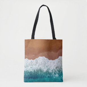 Ocean wave on a sandy beach, background top view tote bag