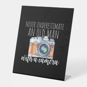 Old Man With A Camera Pedestal Sign