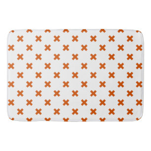 Orange cross stitches on white bath mat