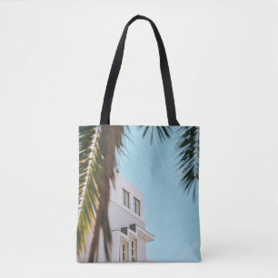 Palm tree near white concrete building tote bag