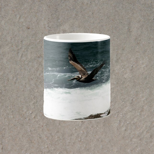 Pelican Flying Over Rocks and Ocean Photograph Coffee Mug (A mug with a photograph of a flying pelican over the Pacific ocean)