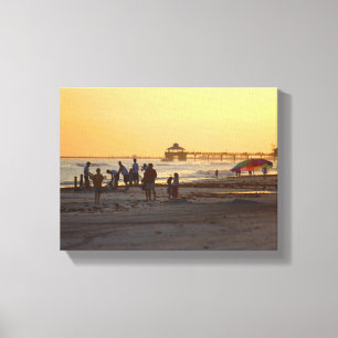 People on the ocean beach at sunset canvas print