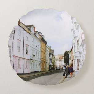 PEOPLE WALKING ON SIDEWALK BESIDE BUILDING AND ROA ROUND CUSHION