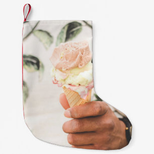 Person holding ice cream cone with three flavors o small christmas stocking