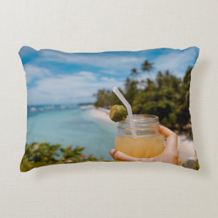 Person holding mason jar with filled with juice at decorative cushion