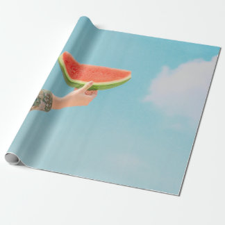 Person holding sliced watermelon wrapping paper