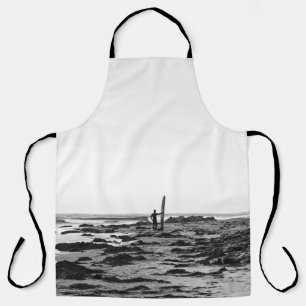 PERSON HOLDING SURFBOARD NEAR BODY OF WATER APRON