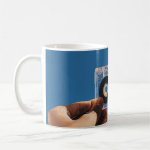 Person holding white and black cassette tape coffee mug