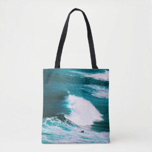 Person on surfboard with ocean waves tote bag