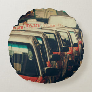 PERSON STANDING NEAR PARKED TAXI DURING DAYTIME ROUND CUSHION