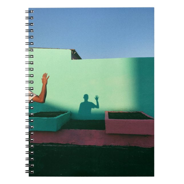 Person waving reflecting shadow on teal wall paint notebook (Front)