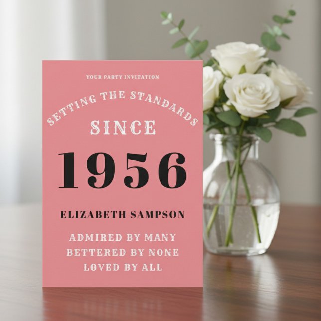 Personalized 70th Birthday 1956 Add Your Name Pink Invitation (1956 Pink invitation on a table with flowers)