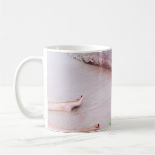 Person's foot beside green shovel on seashore coffee mug