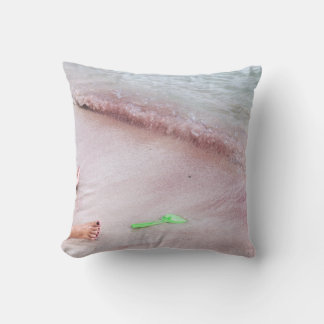 Person's foot beside green shovel on seashore cushion