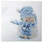 Photo of a Cute Snowman in Winter - Christmas Tile<br><div class="desc">Ceramic tile with a cute photograph of a little snowman. Standing outside in the winter with snow falling all around. This cute little guy is dressed up in blue knitted hat and scarf.</div>