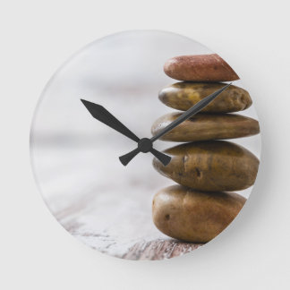 Pile of dark coloured stones on white background round clock