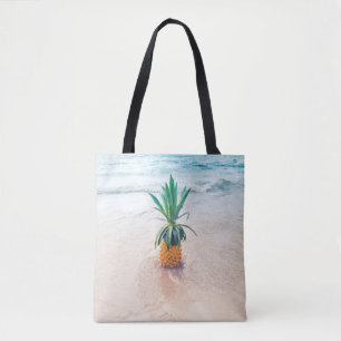Pineapple fruit on beach shore in the morning tote bag