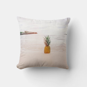 Pineapple on sand near beach cushion