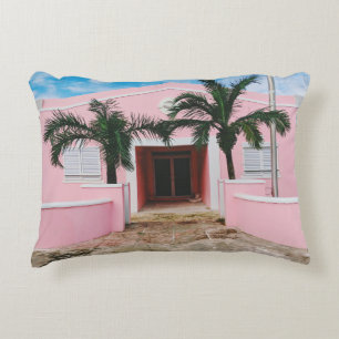 Pink and white concrete house near green trees und decorative cushion