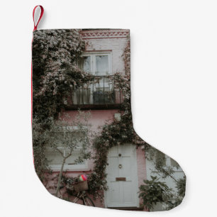 PINK AND WHITE PAINTED HOUSE COVERED WITH PLANTS A SMALL CHRISTMAS STOCKING