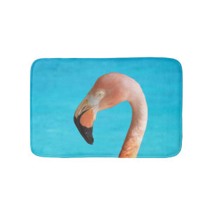 Pink flamingo face against blue water on bath mat