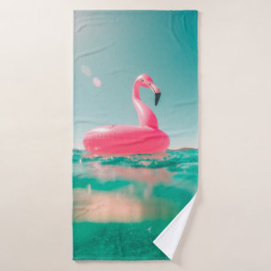 Pink flamingo swim ring on body of water in summer bath towel
