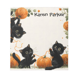 Playful Black Cat with Pumpkin-Inspired Orange Notepad