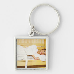 Portrait of a young woman lying in a sauna key ring