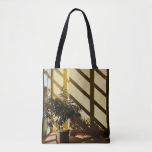 Potted green plant on brown wooden table tote bag