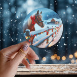 Pretty Brown Horse with Bow Christmas   Classic Round Sticker<br><div class="desc">Christmas stickers. A pretty brown horse with a red bow on his neck standing behind an old rustic wood fence with a snowy background and vintage old red barn.</div>