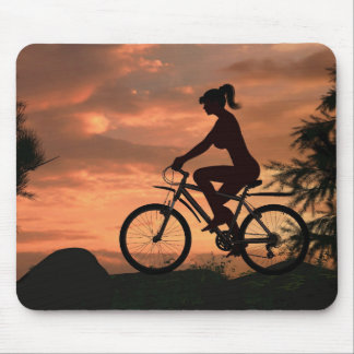 Pretty girl riding her bike at sunset mouse mat