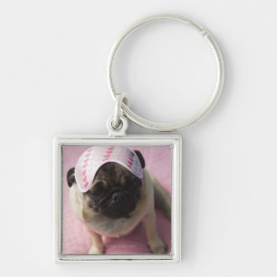 Pug dog with eye mask on head sitting on bed, key ring