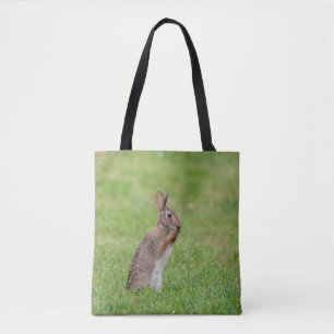 Rabbit standing in the grass and looking shy tote bag