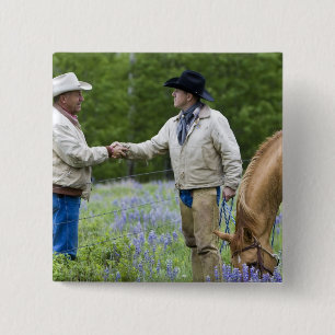 Ranchers shaking hands across the fencing in 15 cm square badge