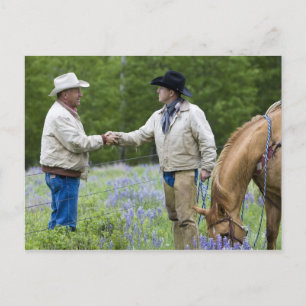 Ranchers shaking hands across the fencing in postcard