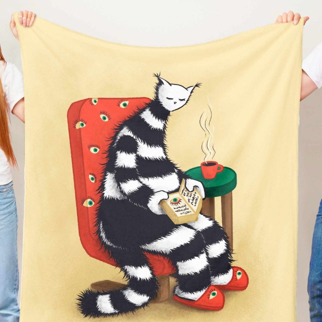 Reading Cat Book Lover Fleece Blanket (light beige blanket with weird reading cat character with book and coffee illustration held in hands)