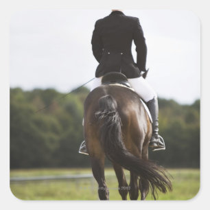 rear view of female dressage rider exercising square sticker