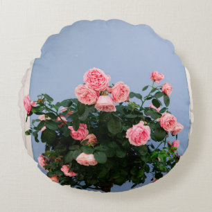 Red flowers with green leaves on blue wall round cushion