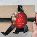 Red gold baubles Christmas Classic Round Sticker<br><div class="desc">For a Christmas party favours or gift wrapping. A red uneven coloured background. Decorated with red and gold baubles and some greenery and a pine cone.  Personalise and add your name,  year.  Text: Merry Christmas</div>