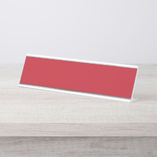 Red, pink, and orange garments hang side by side o desk name plate