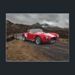 Red Sports Car Postcard<br><div class="desc">A photograph of a red convertible sports car photo Tasks on a country road with a backdrop of snowy mountains by the photographer Dave Fletcher</div>