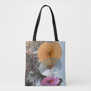 Red umbrella on green tree tote bag
