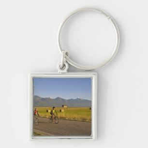 Road bicyclists ride down a back country road key ring