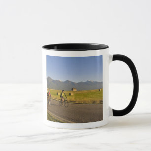 Road bicyclists ride down a back country road mug