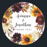 Rustic Autumn Floral Wedding Thank You Favour Classic Round Sticker<br><div class="desc">Dramatic fall flowers include yellow sunflowers, purple peonies, dark red roses, and ivory white hydrangeas. They are nestled in fall leaves and vines to create a very pretty wreath. The wedding couple names are written in a large script font. Thank you sentiment follows This wedding sticker is part of the...</div>